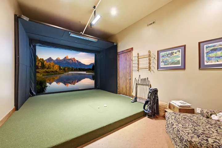 Dedicated indoor golf simulator with an expansive screen and a golf turf playing surface