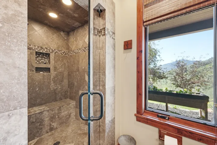 Tiled shower enclosure featuring a built-in bench, recessed lighting, and mosaic tile accents