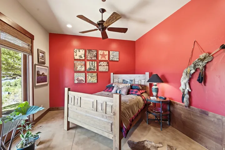 Room featuring an accent wall, wood-finish flooring, a ceiling fan, a window with exterior scenery, and wood trim