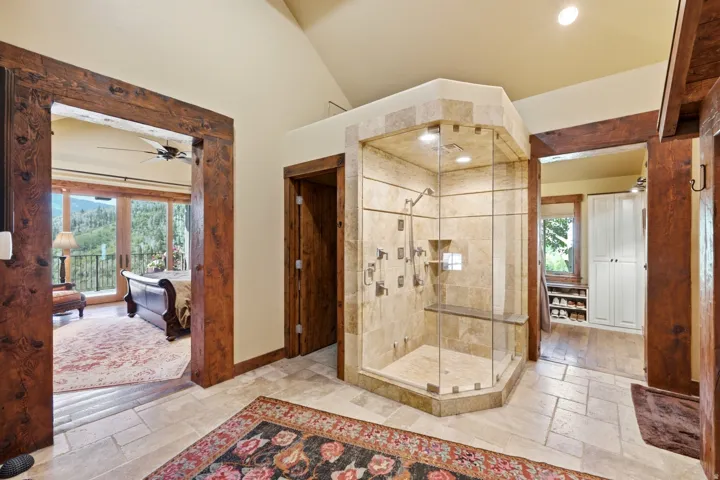 Expansive walk-in shower with multiple showerheads, integrated seating, and full-height tile enclosure
