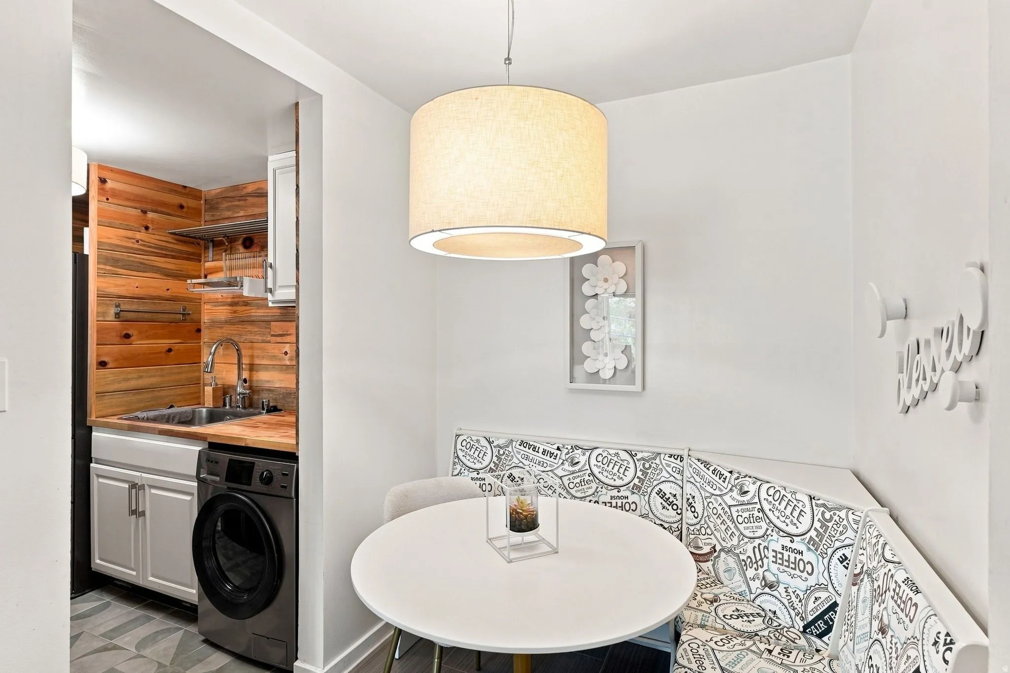 Compact kitchen area featuring wood-plank wall paneling, a stainless steel sink with a gooseneck faucet, and a built-in washer unit