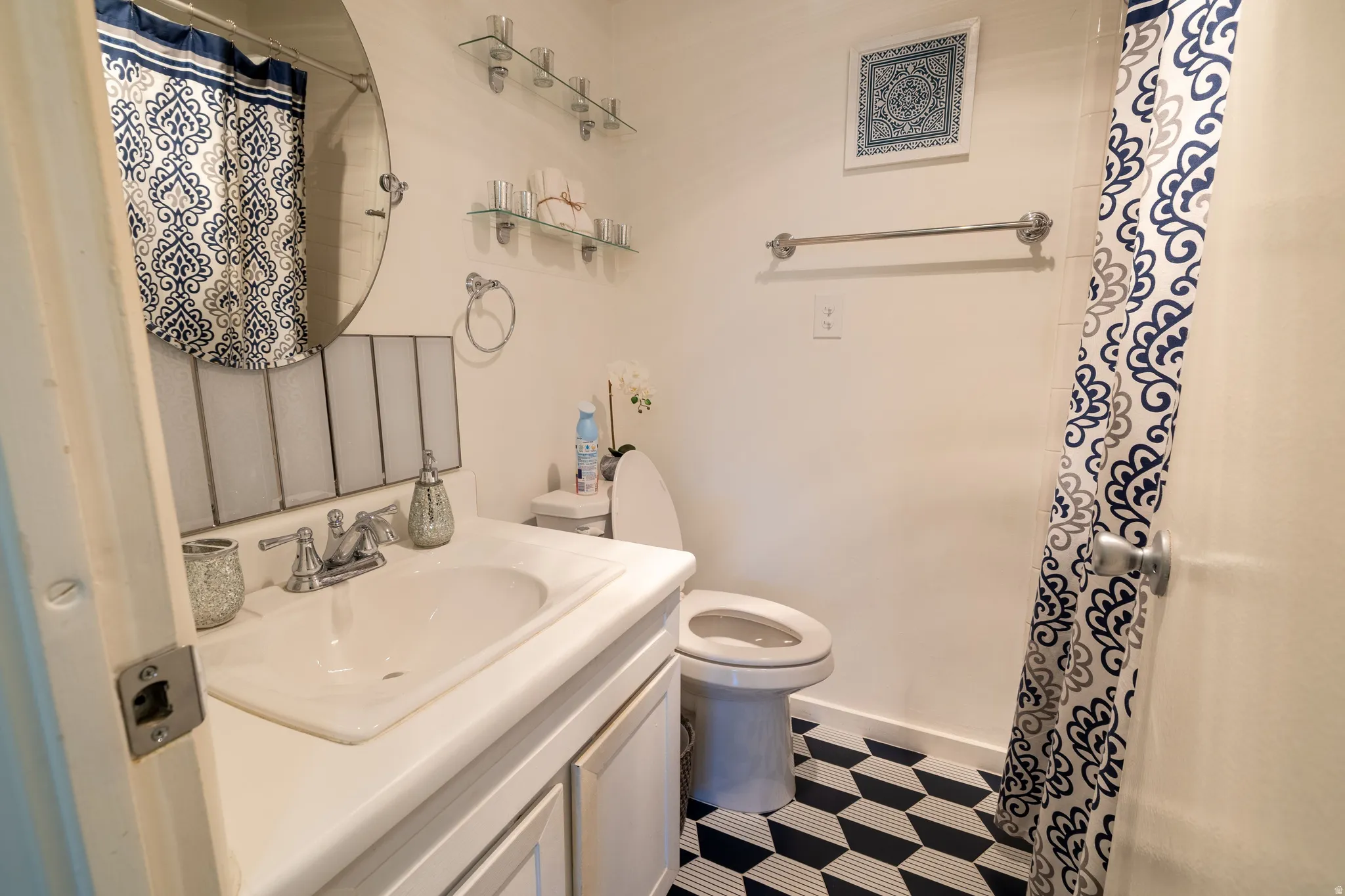 Bathroom featuring a vanity with an integrated sink, polished chrome faucet, and a round mirror