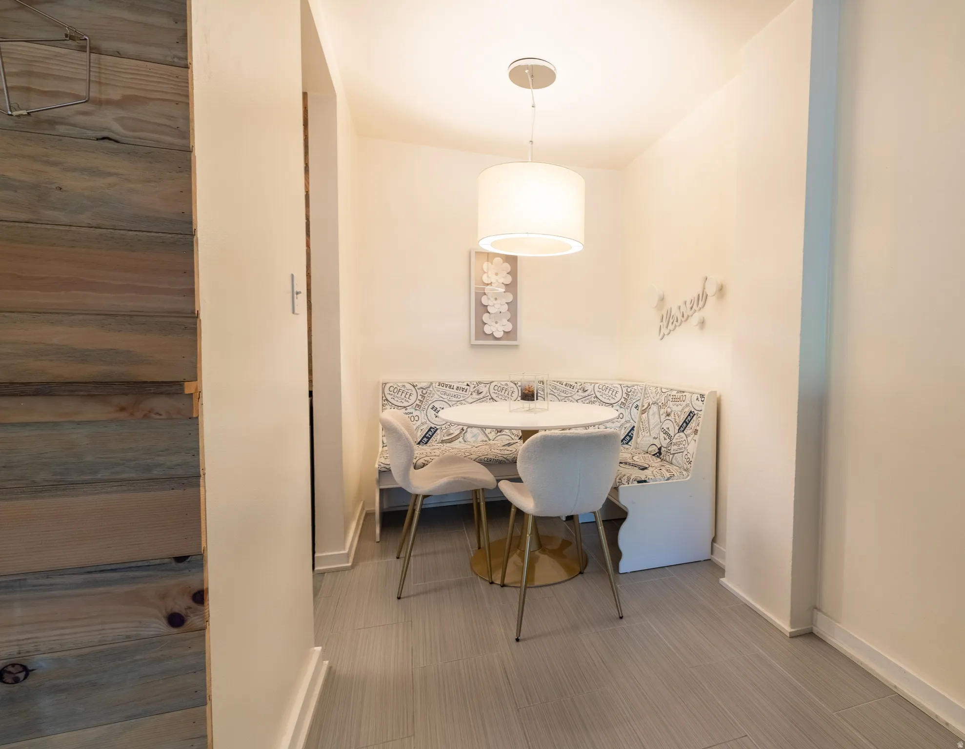Dining nook featuring built-in banquette seating with decorative upholstery, a circular pedestal table, and a contemporary drum pendant light fixture