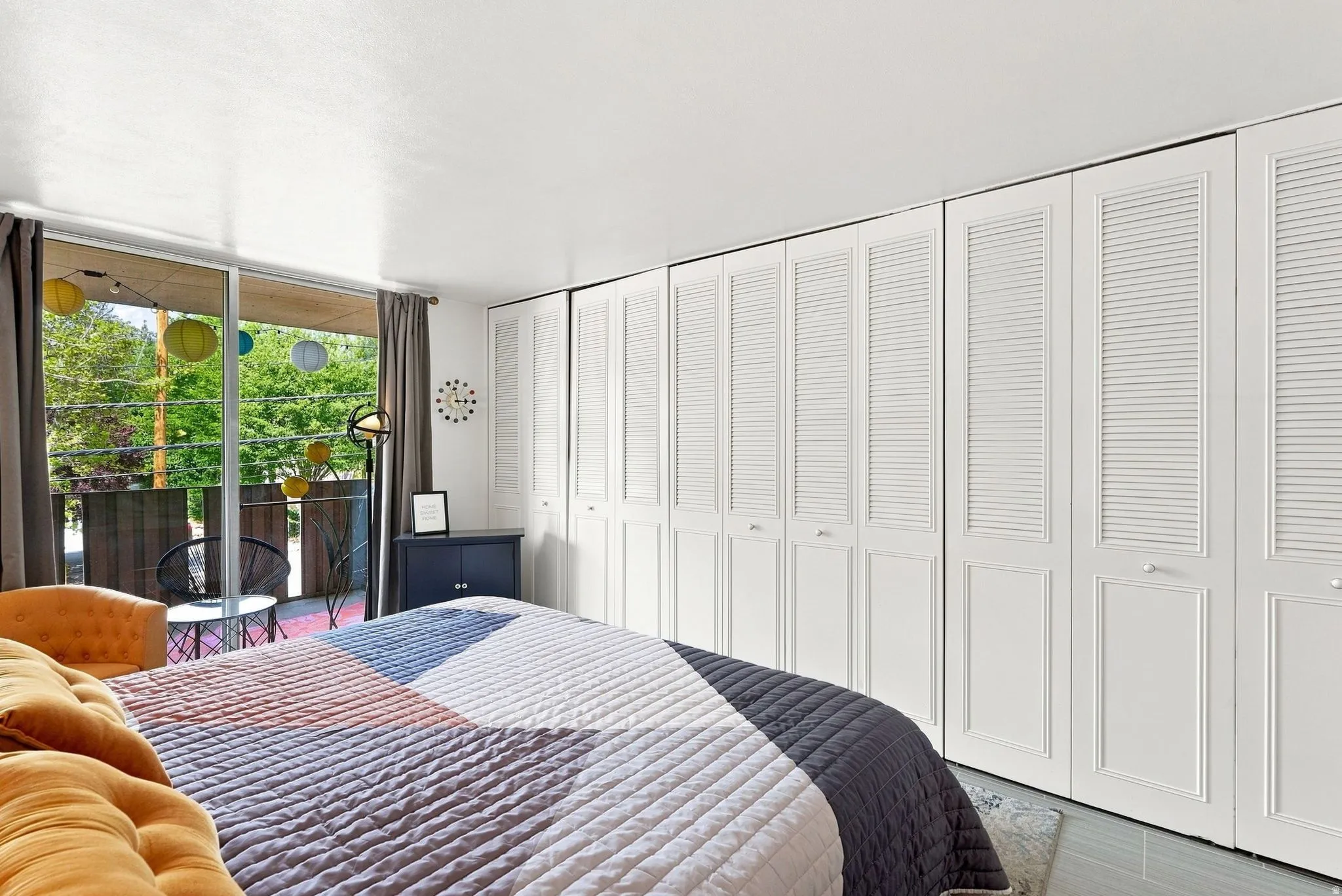 Extensive built-in storage with louvered doors, sleek white walls, light-colored flooring, and large sliding glass doors opening to an exterior balcony