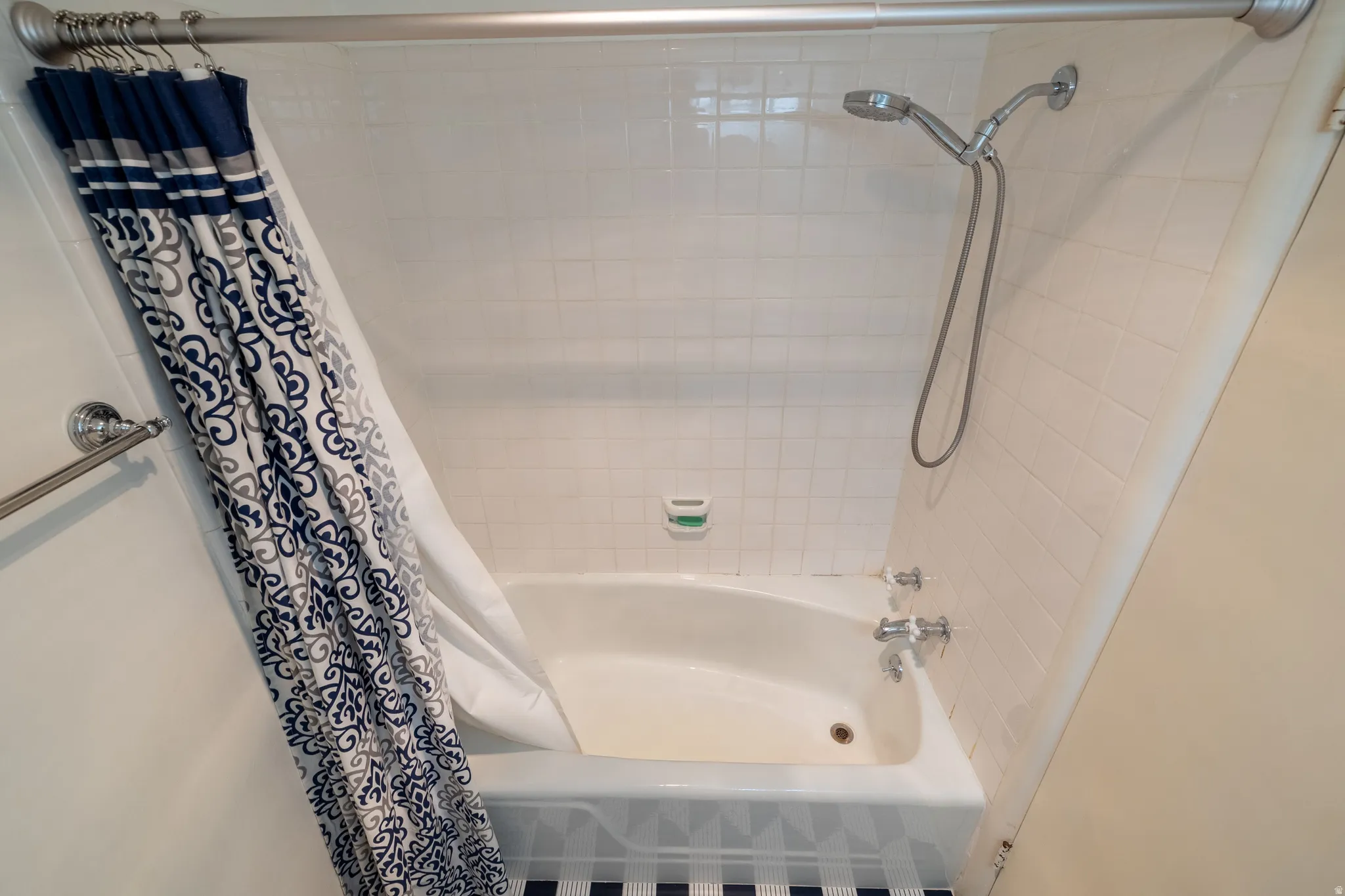 Bathtub and shower combination featuring white subway tile surround, polished chrome fixtures, and a curved shower rod