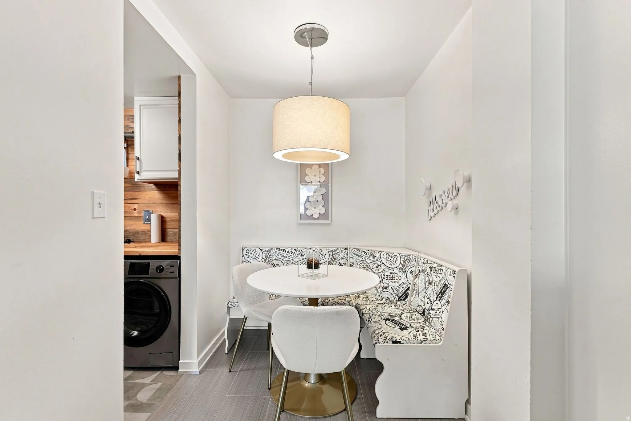 Recessed dining nook with built-in bench seating, overhead drum pendant lighting, and wood-finish flooring