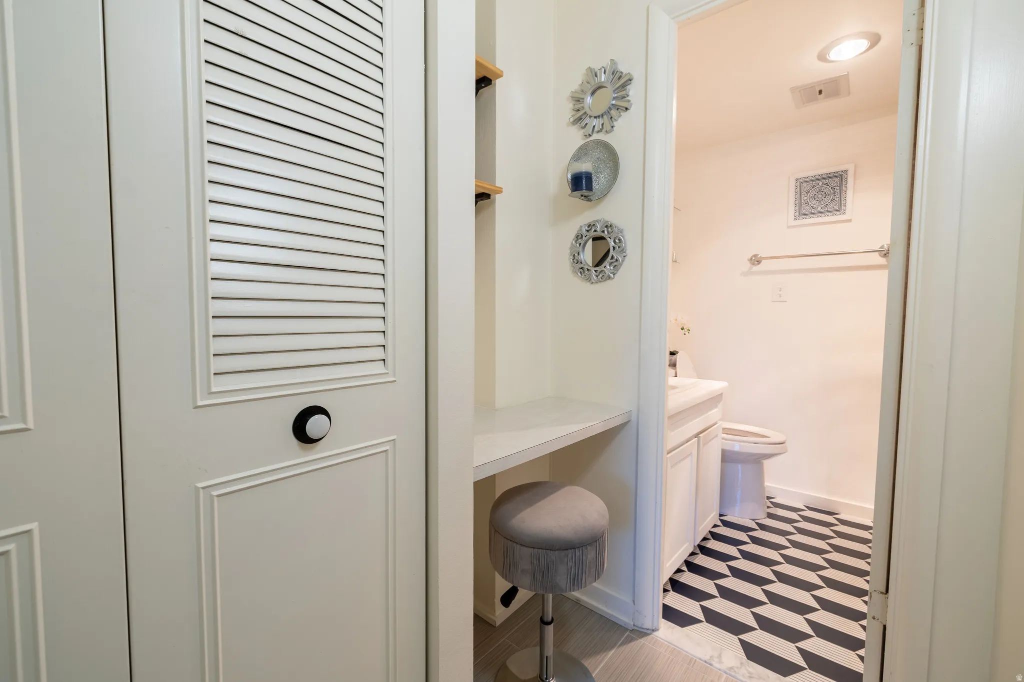 Bathroom with geometric tile flooring, a white vanity with a rectangular sink, and a toilet