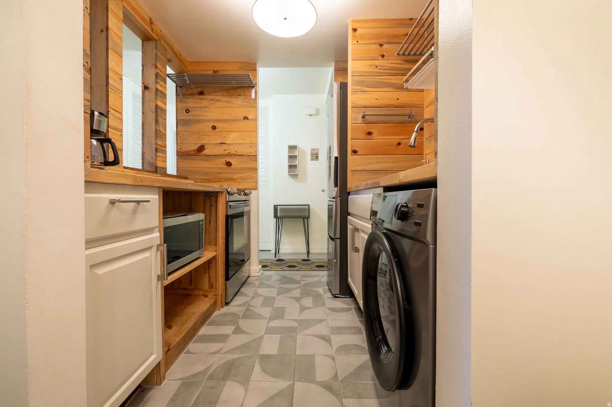 Galley-style kitchen featuring wood-paneled walls and a patterned tile floor