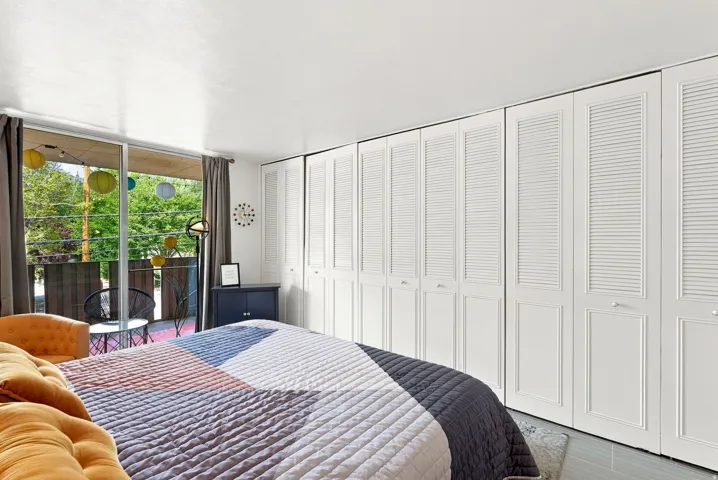 Extensive built-in storage with louvered doors, sleek white walls, light-colored flooring, and large sliding glass doors opening to an exterior balcony