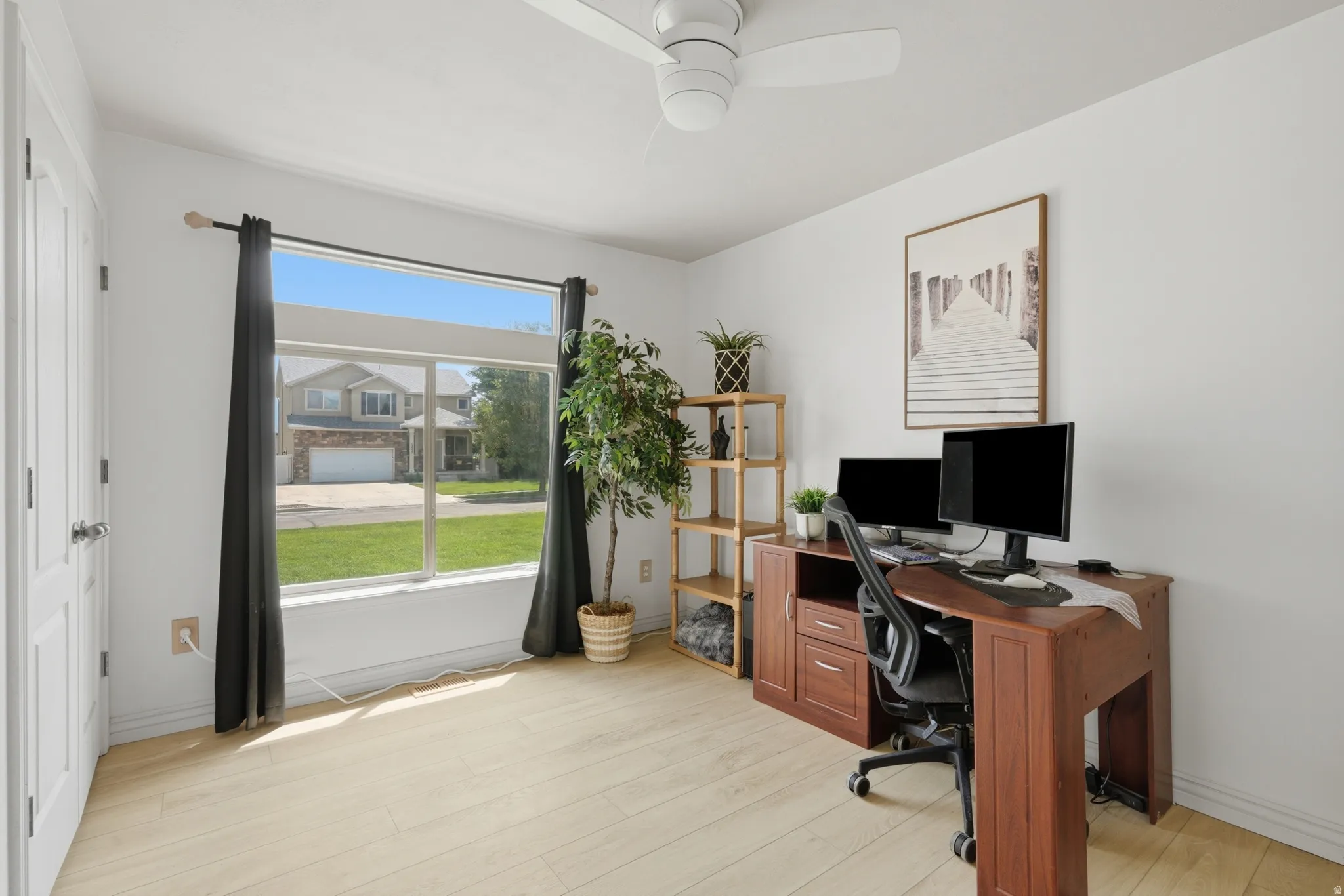 Bright room featuring light wood-finish flooring and a ceiling fan
