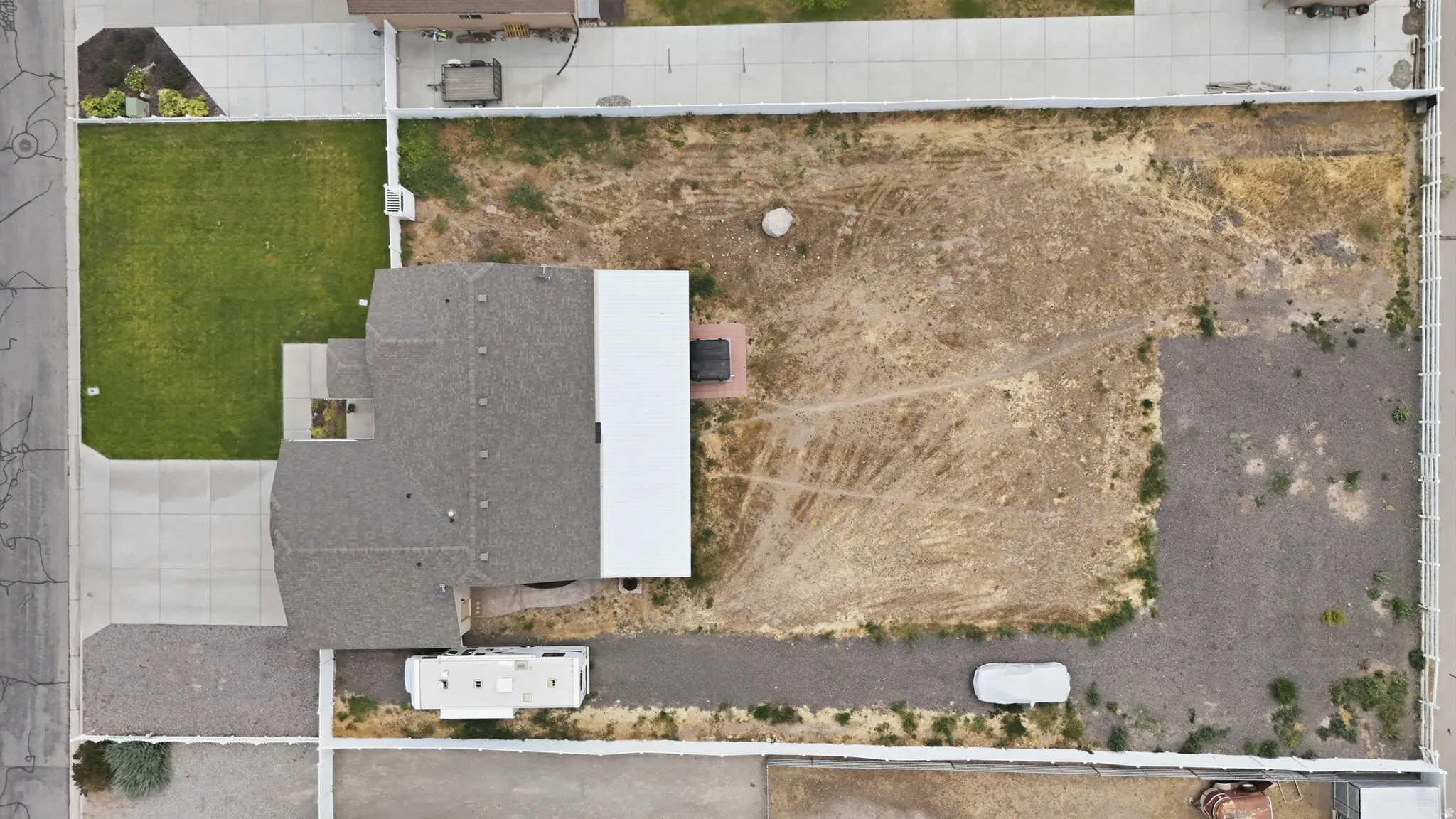 Expansive property featuring a grey shingle roof, concrete driveway, and a large undeveloped lot