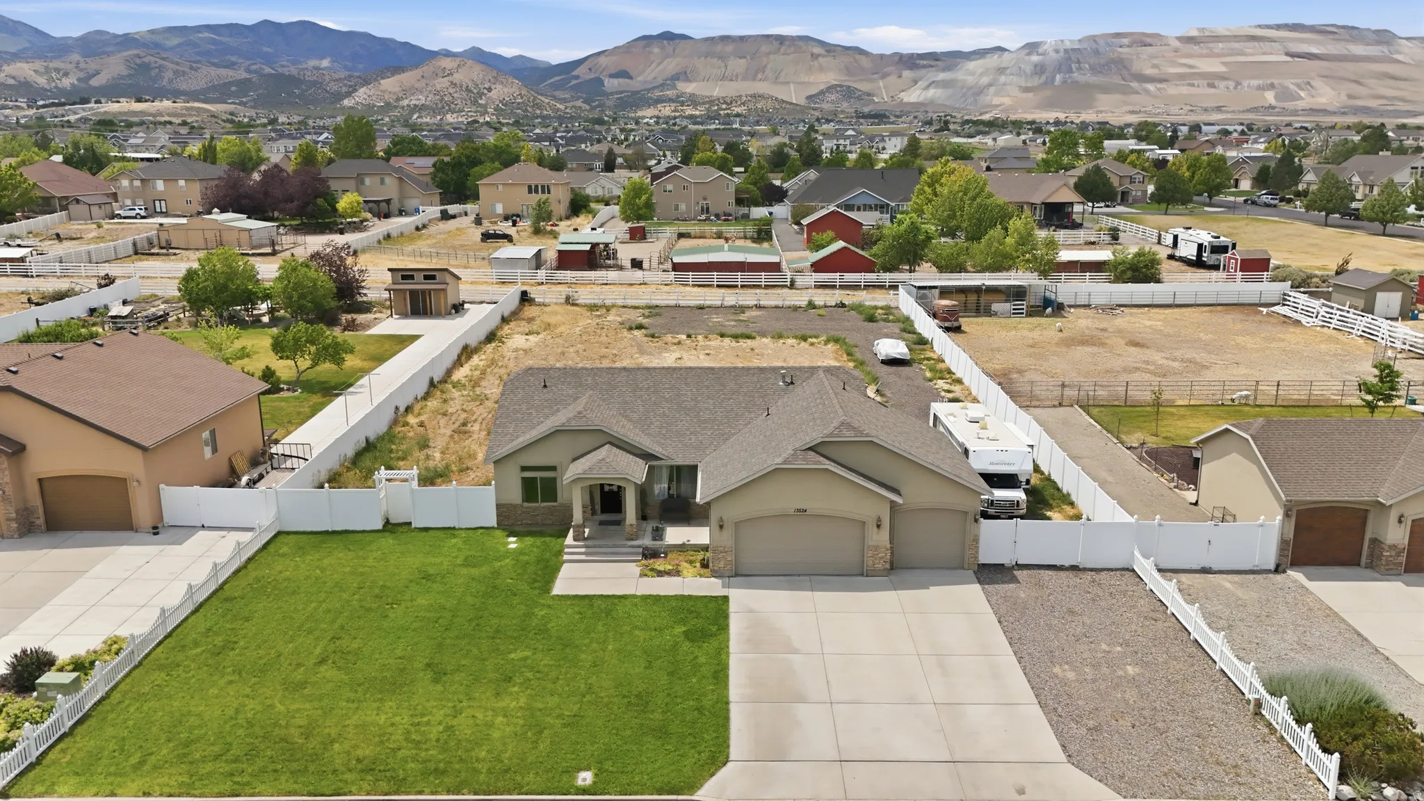 Ranch-style residence featuring a prominent garage, a manicured front lawn, and a paved driveway