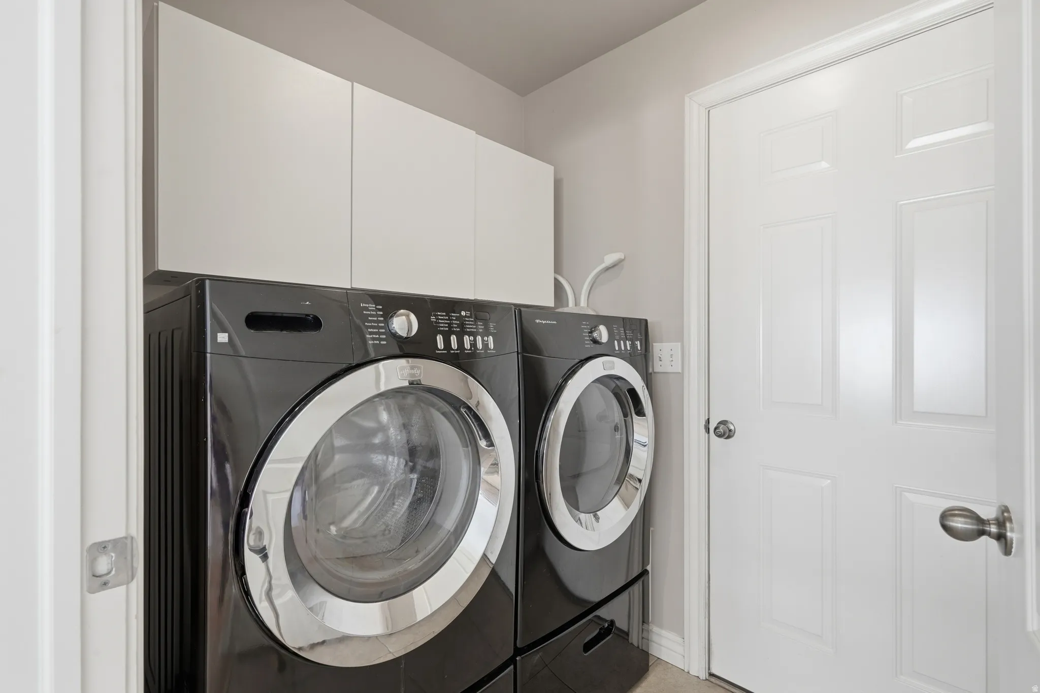 Laundry area featuring white upper cabinetry, light gray wall paint, and white trim