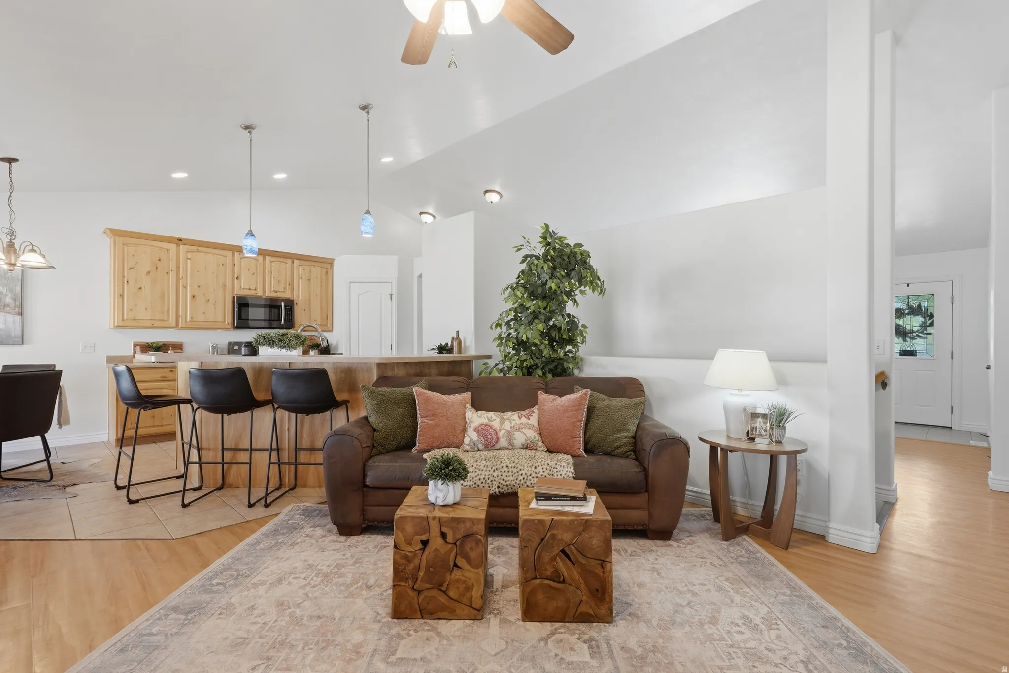 Open-concept living area featuring light wood-finish flooring, a vaulted ceiling, and recessed lighting