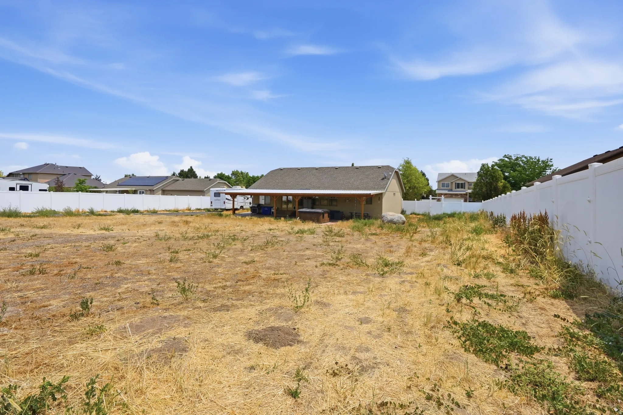Expansive backyard featuring a covered patio, vinyl fencing, and open space for customization
