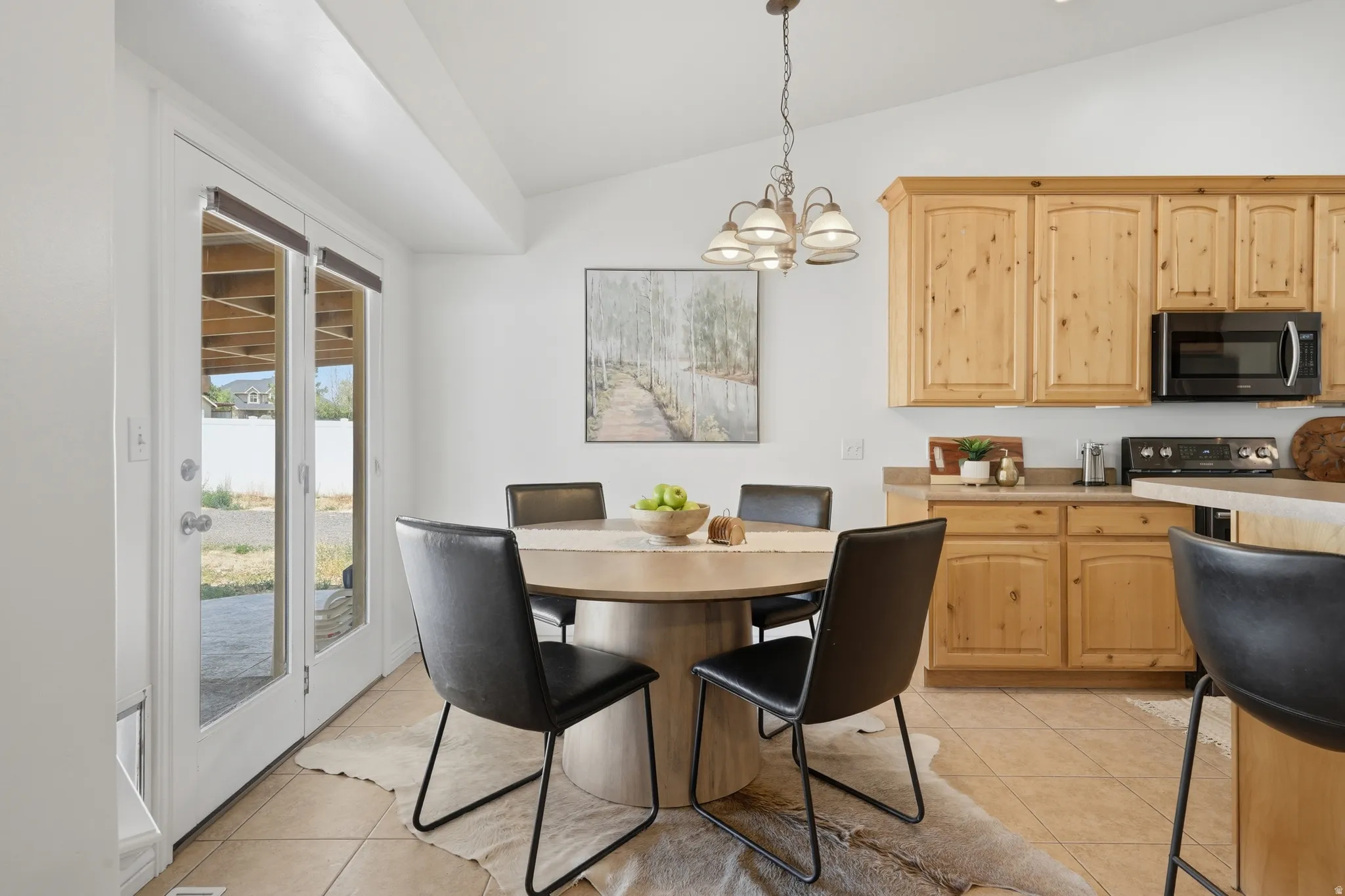 Kitchen-dining area featuring natural wood cabinetry, integrated microwave, and a breakfast bar