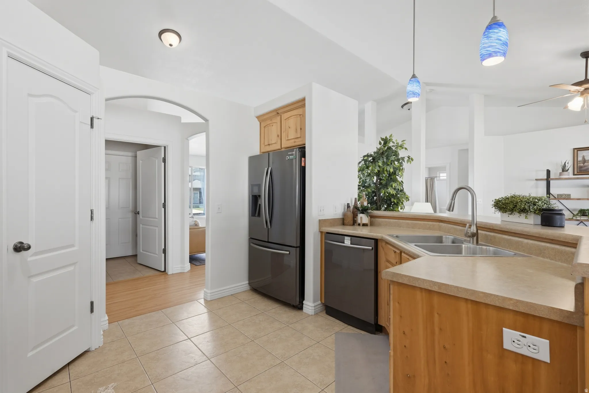 Kitchen featuring stainless steel appliances, light wood cabinetry, and a corner sink