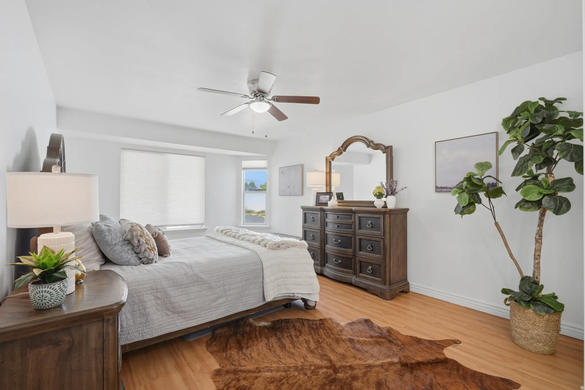 Bedroom featuring wood-finish flooring, a ceiling fan with integrated lighting, and white baseboards