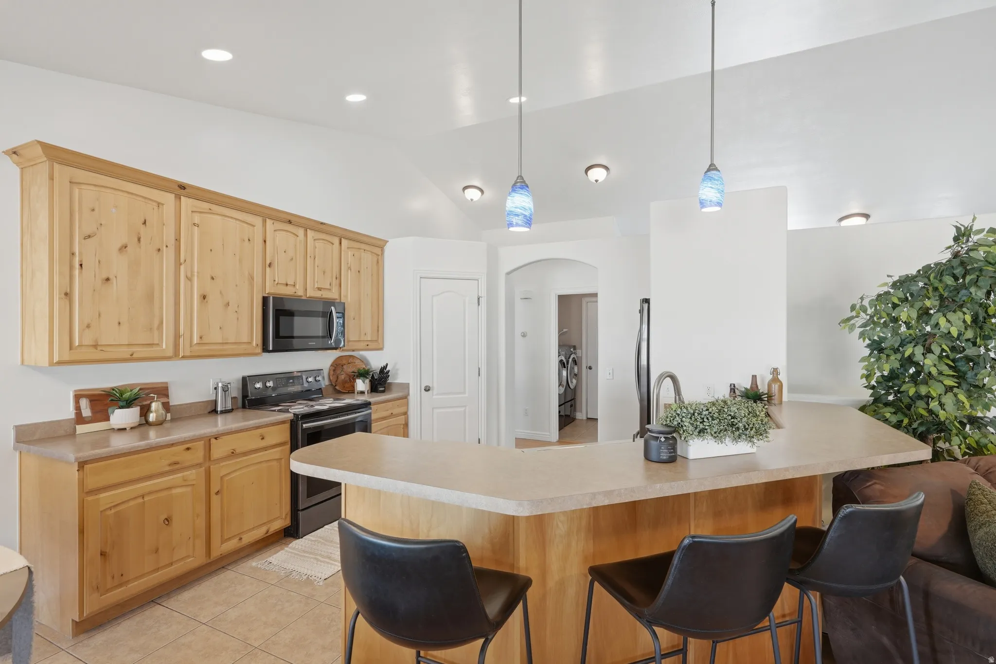 Kitchen featuring light wood cabinetry, a built-in microwave, and a black range