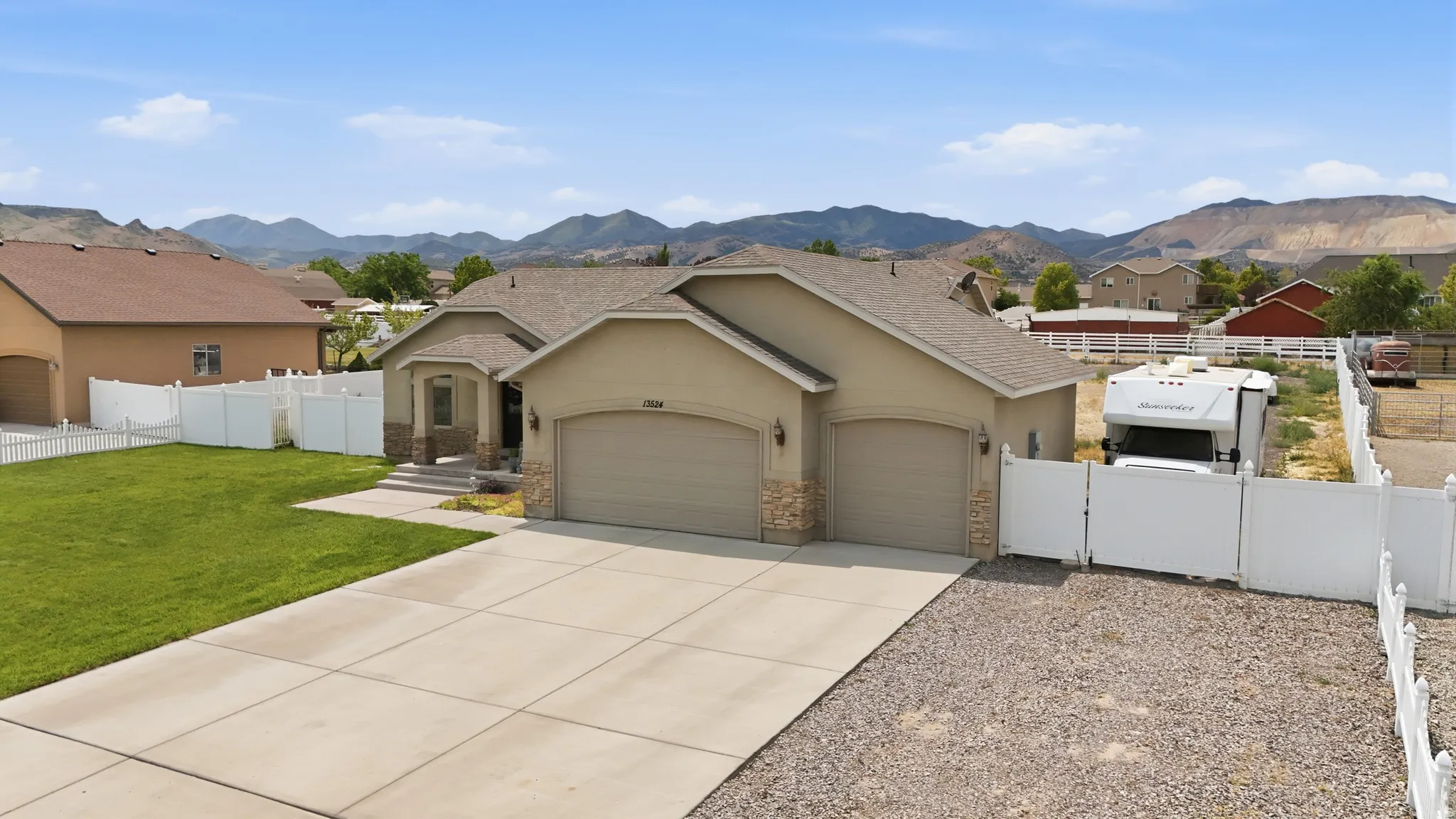 Single-story stucco residence with a two-car garage, stone accents, and a covered entry