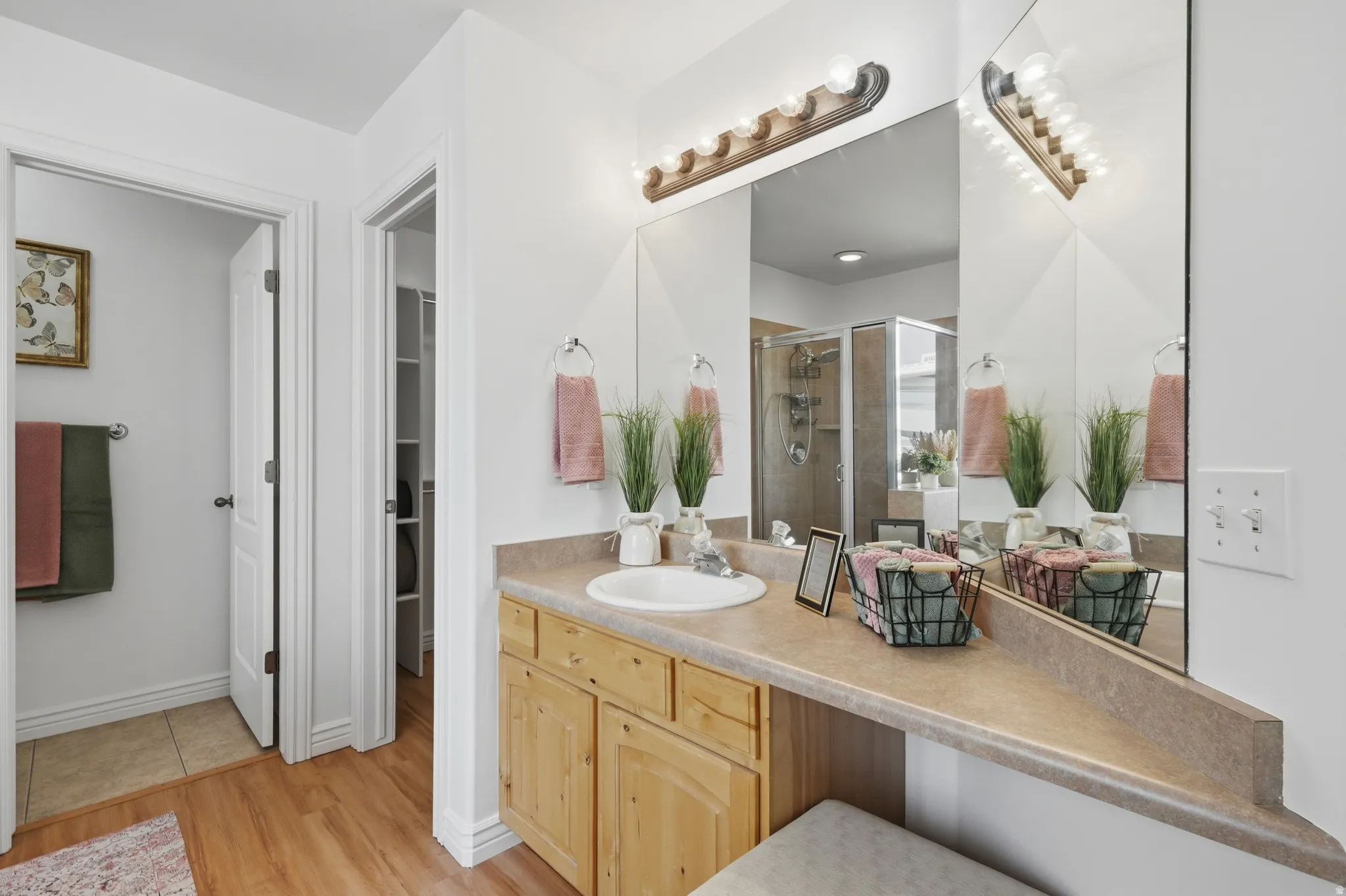 Bathroom featuring a vanity with a laminate countertop, integrated sink, and light wood cabinetry