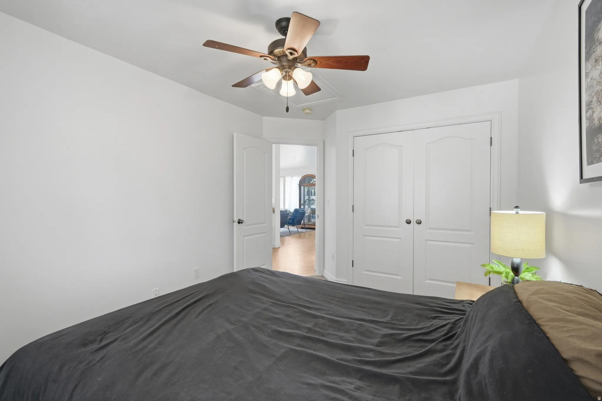 Room featuring light-toned walls, wood-finish flooring visible in the doorway, and a ceiling fan with integrated lighting