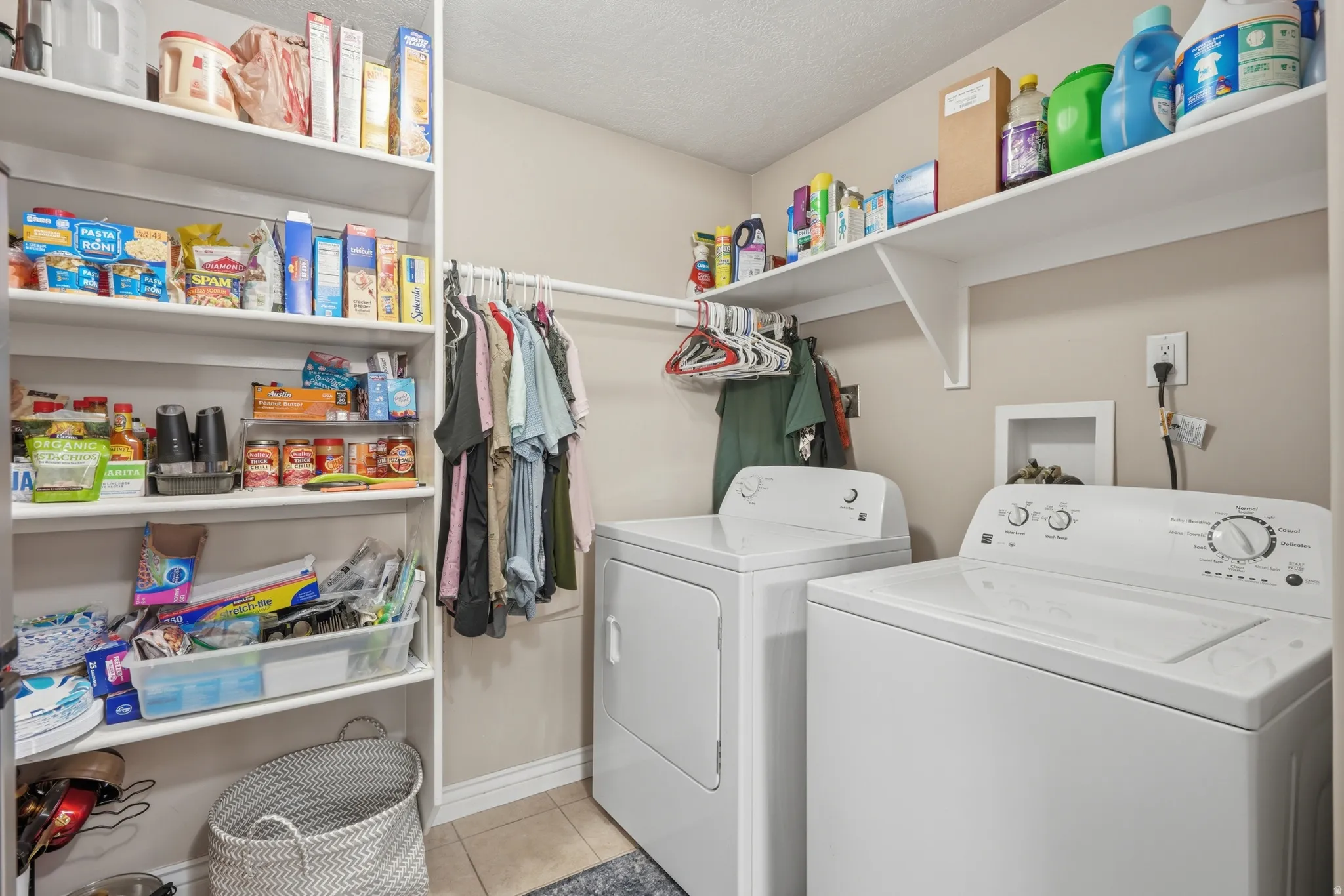 Dedicated laundry area featuring a washer and dryer, integrated shelving, and a clothes hanging rod