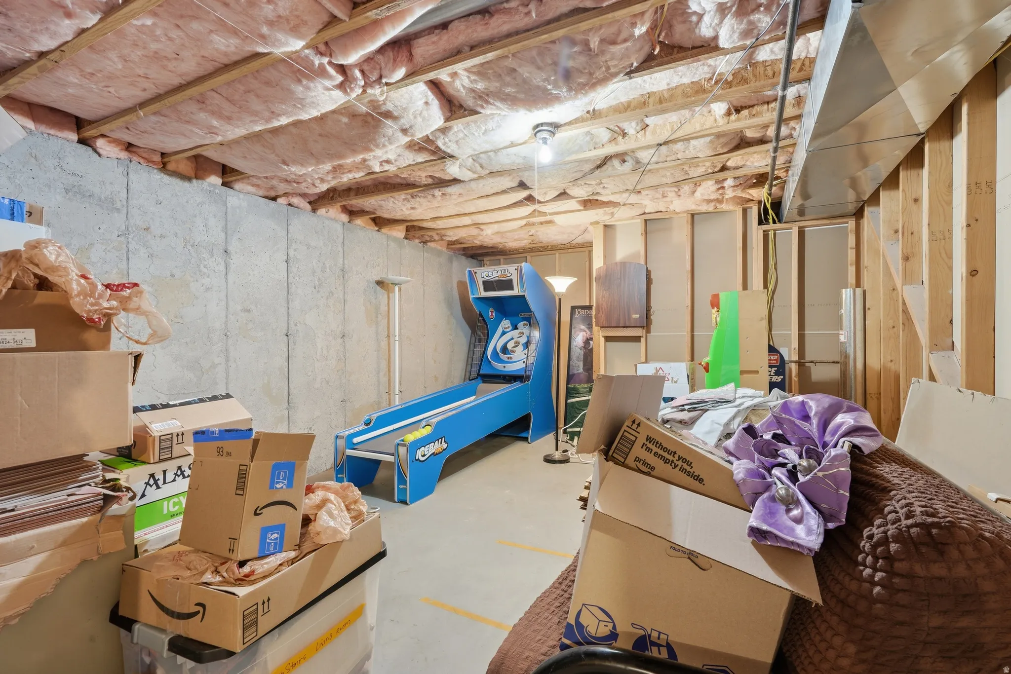 Unfinished basement featuring exposed insulation, concrete foundation walls, bare wood framing, and a concrete floor