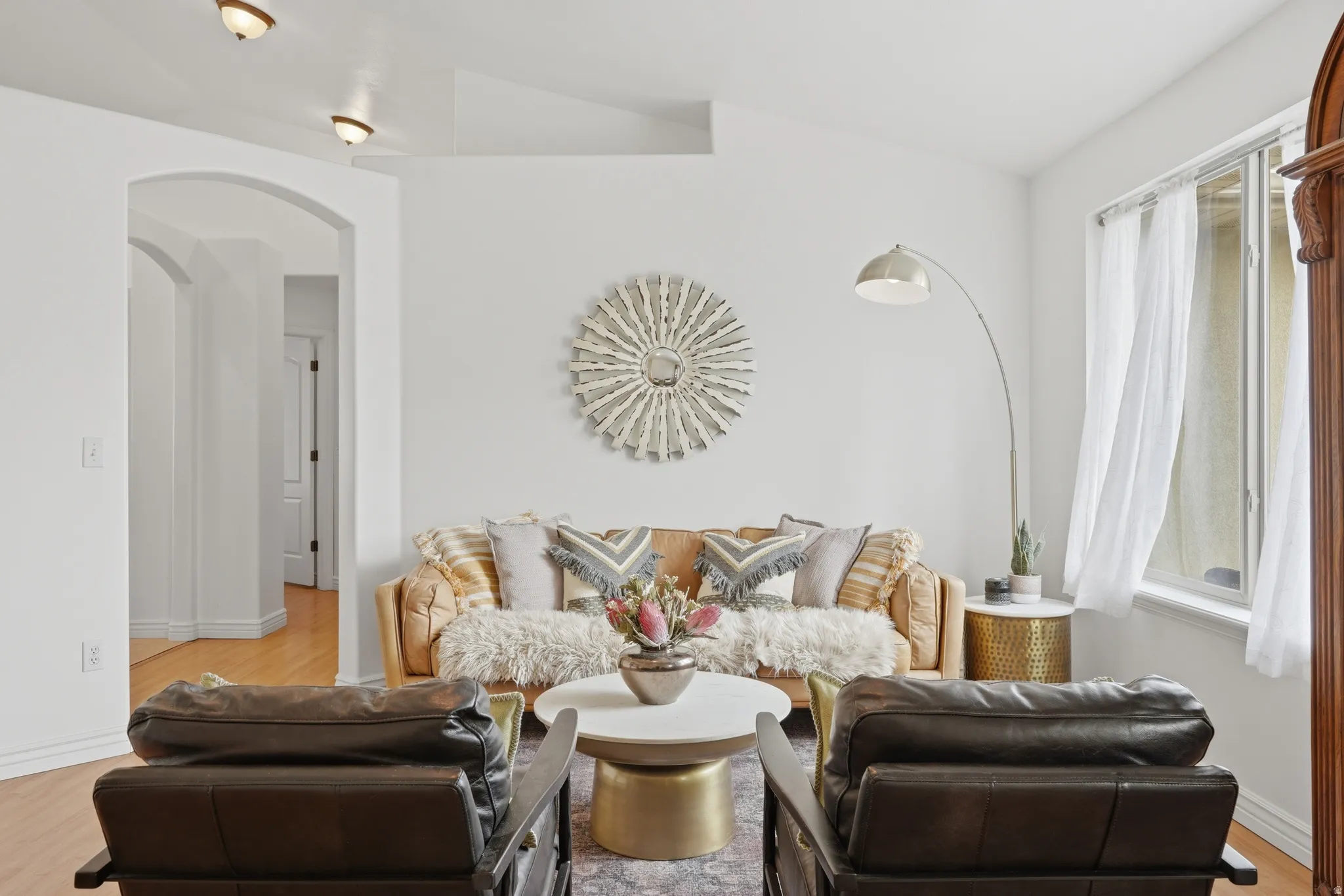 Living area featuring vaulted ceilings, light wood-finish flooring, an arched doorway, and recessed ceiling lighting