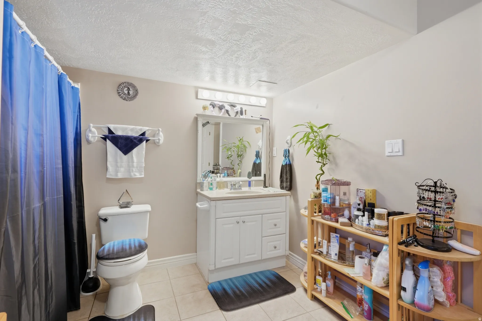 Bathroom featuring a white vanity with built-in storage, a wall-mounted mirror, and overhead vanity lighting