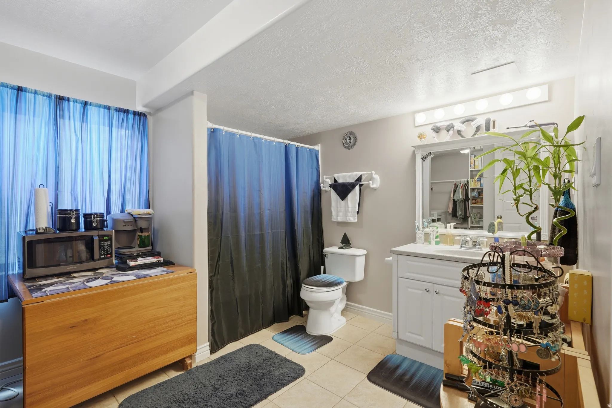 Bathroom with tile flooring, white vanity with integrated sink, and wall-mounted light fixture