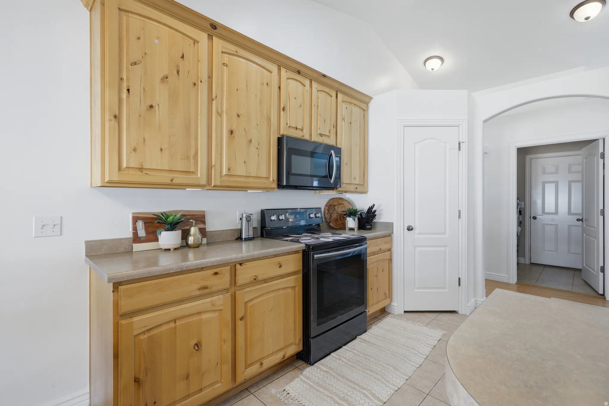 Kitchen featuring wood-finish cabinetry, light-toned countertops, and tile flooring