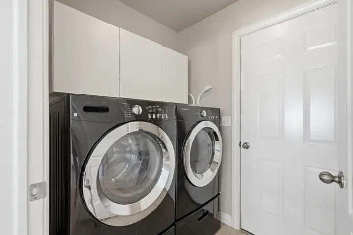Laundry area featuring white upper cabinetry, light gray wall paint, and white trim