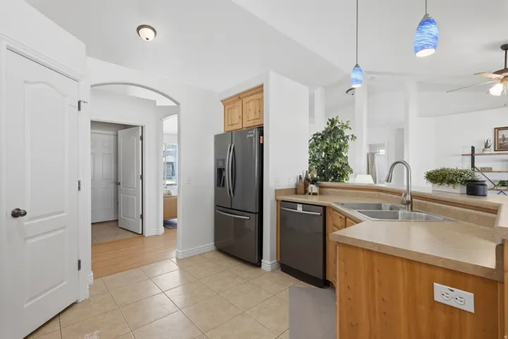 Kitchen featuring stainless steel appliances, light wood cabinetry, and a corner sink