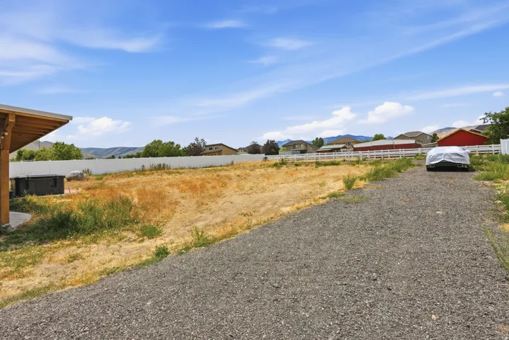 Expansive gravel driveway leading to a large undeveloped lot