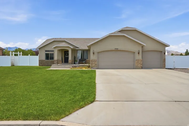 Spacious single-story residence featuring a stucco exterior with stone accents, a multi-car garage, and a broad concrete driveway