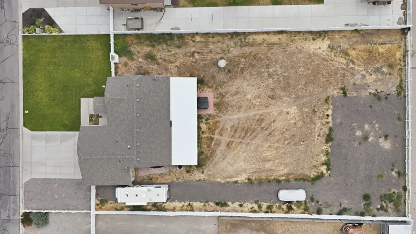 Expansive property featuring a grey shingle roof, concrete driveway, and a large undeveloped lot