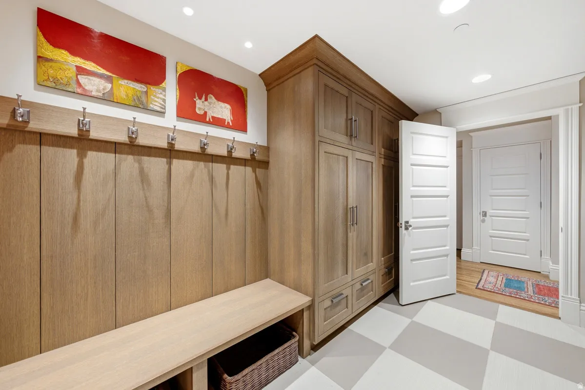 Custom built-in cabinetry and bench seating featuring wood-finish paneling and brushed nickel hooks
