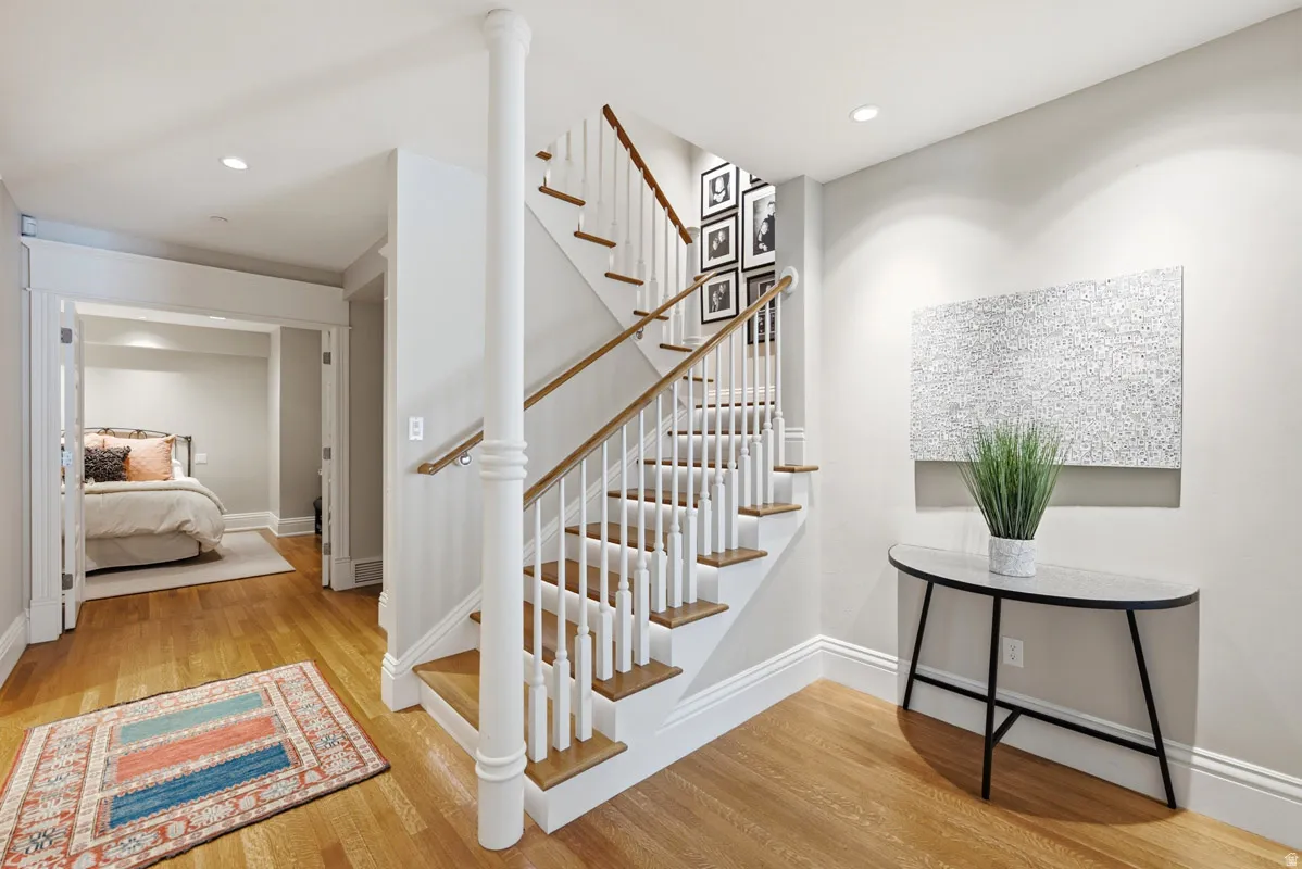 Hardwood flooring extends through the entryway, featuring a prominent staircase with white risers and wood treads