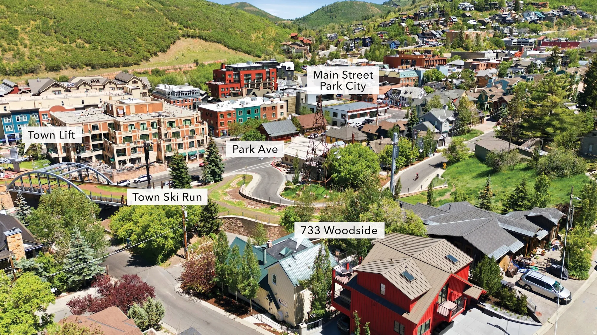 Aerial perspective showcasing a vibrant mountain town, surrounded by green hillsides