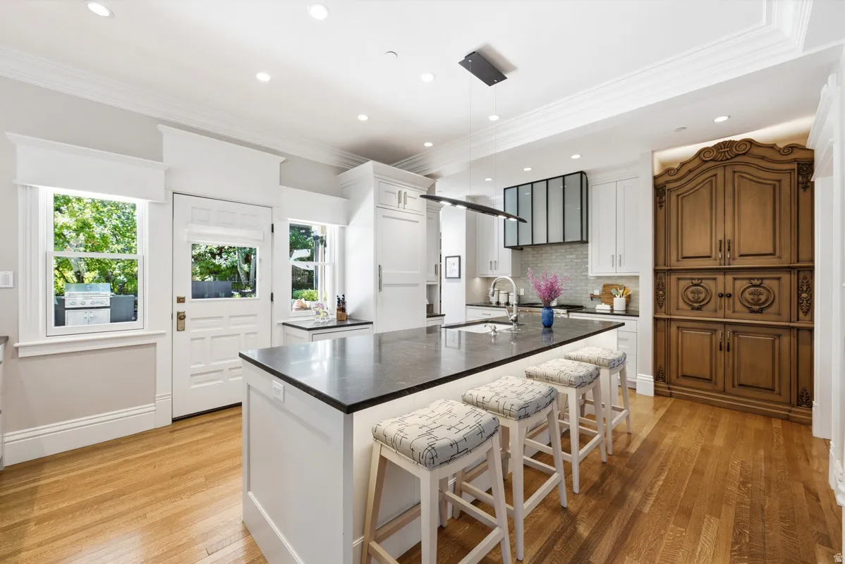 Contemporary kitchen featuring a large central island with seating, a dark countertop, and integrated sink