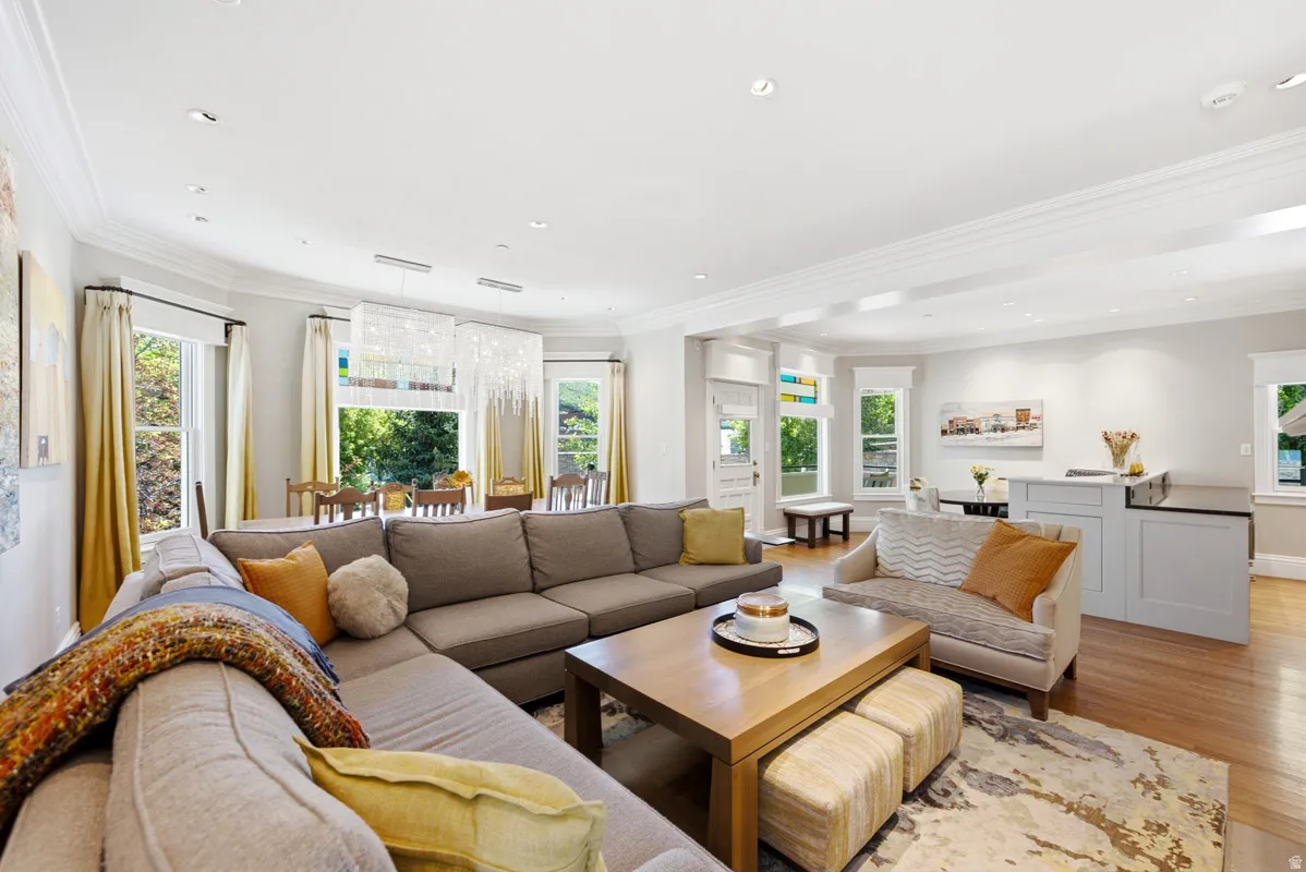 Open-concept living area featuring wood-finish flooring throughout, recessed lighting, and crown molding