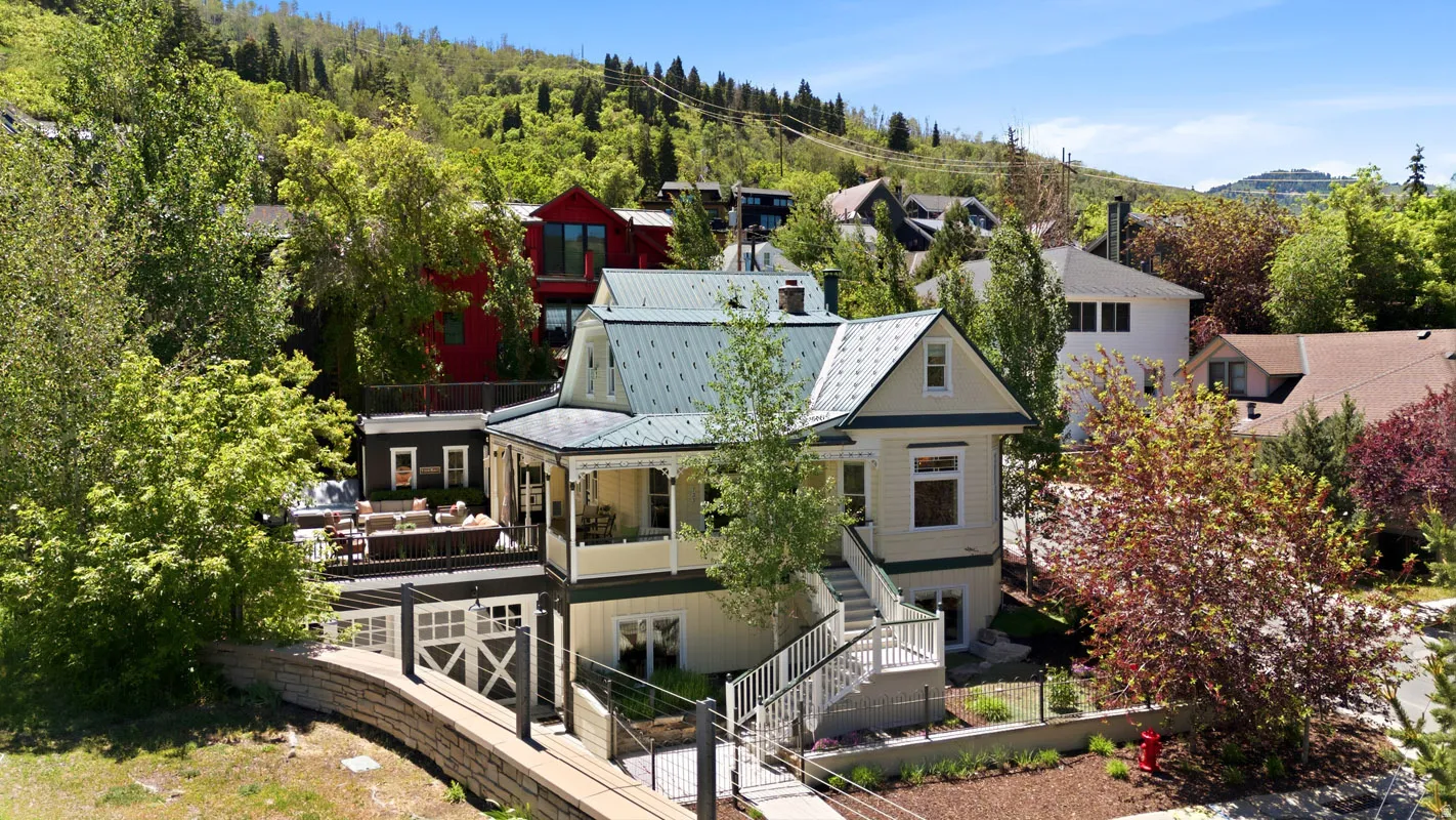 Multi-level residence featuring a light-colored exterior, a gabled roofline, and a prominent front porch with decorative railings