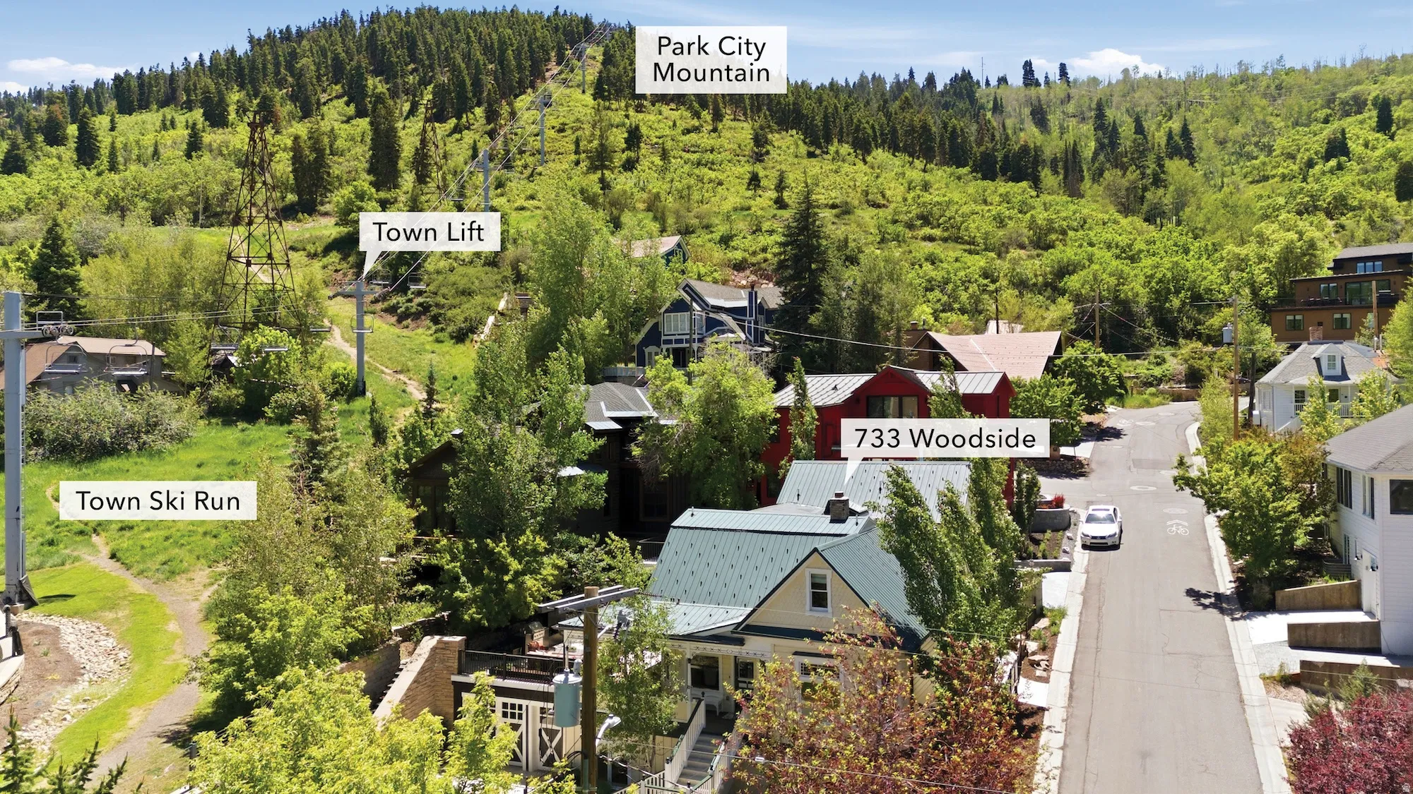 Aerial perspective showcasing the property at 733 Woodside, surrounded by mature trees and verdant hillside