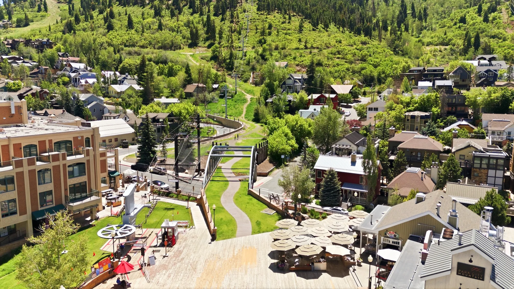 Townscape featuring a mix of residential and commercial buildings, lush green hillsides, and a pedestrian pathway