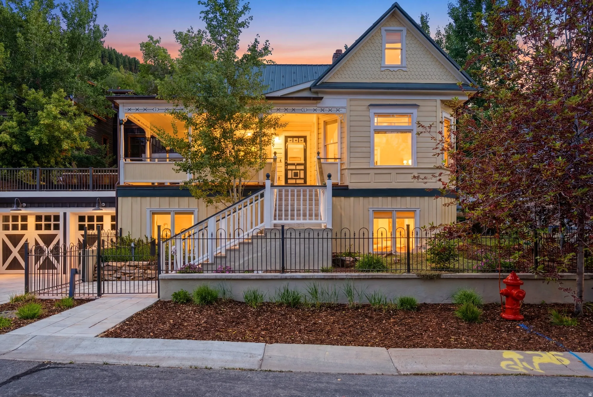 Charming multi-level residence featuring a covered front porch, white-railed staircase, and decorative metal fencing