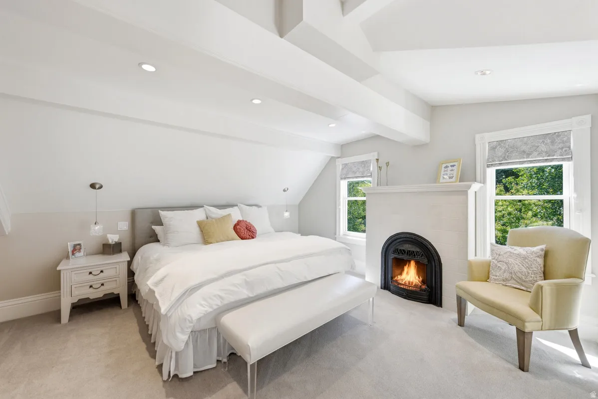 Vaulted ceiling with exposed beams, recessed lighting, and a built-in fireplace featuring a black arch insert
