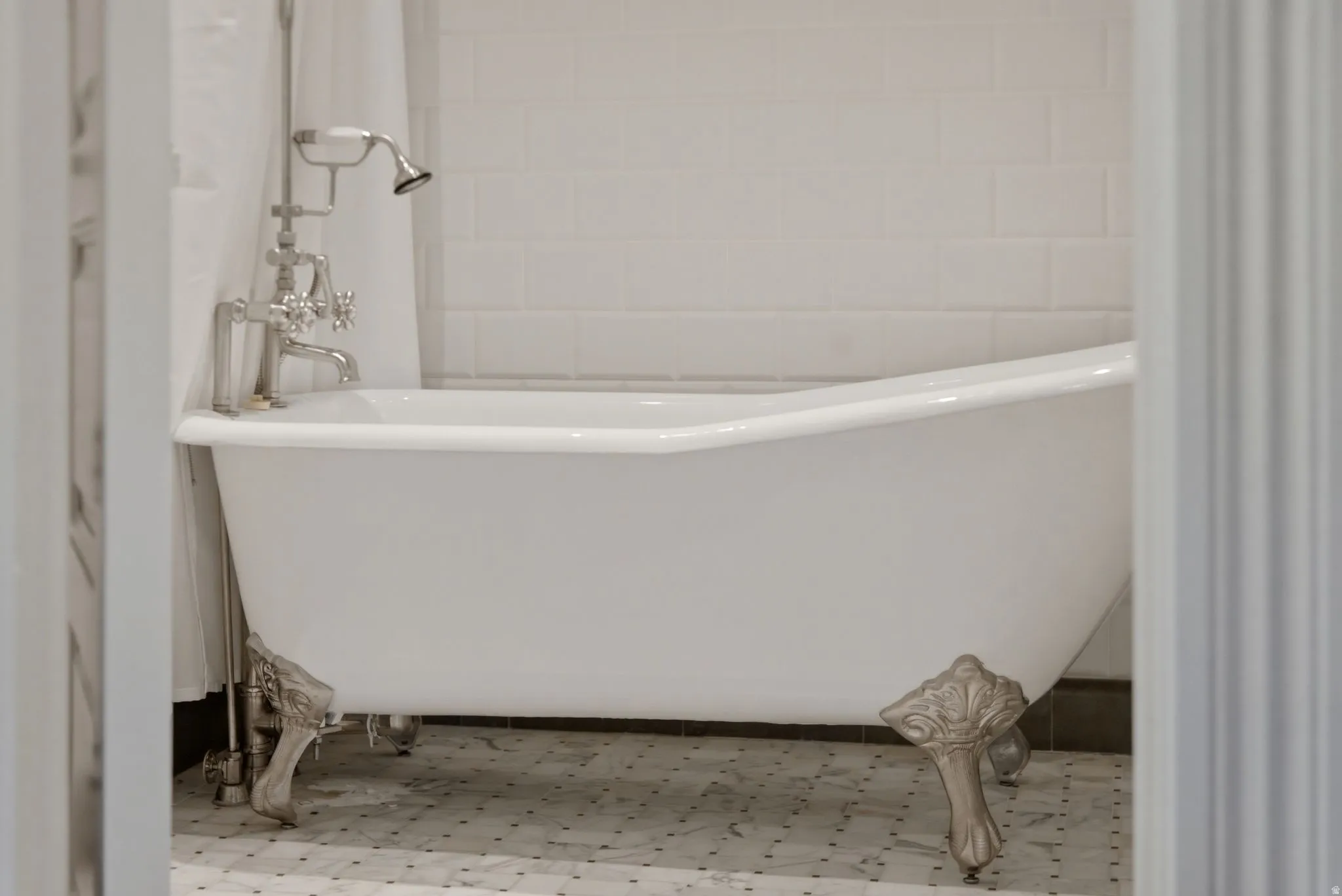 Freestanding clawfoot bathtub featuring polished chrome fixtures and a handheld shower
