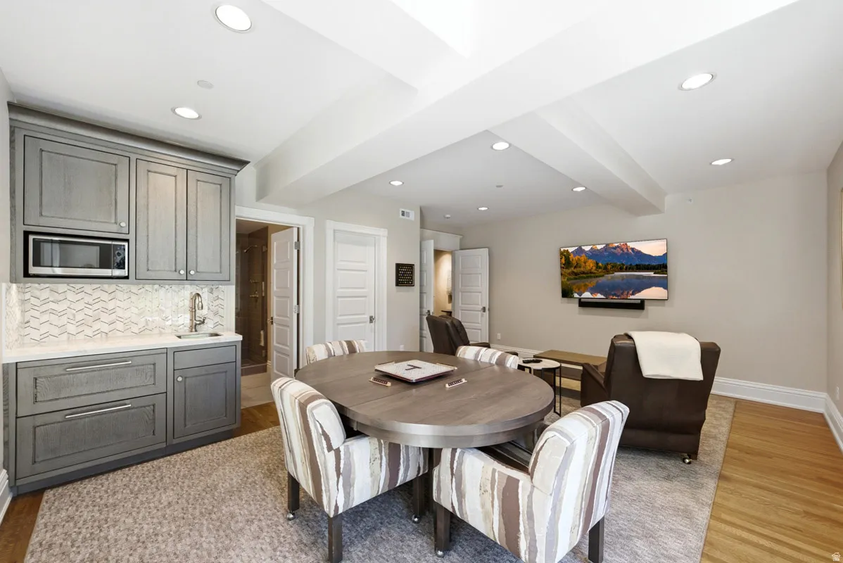 Wet bar featuring gray cabinetry, integrated microwave, and a white patterned tile backsplash