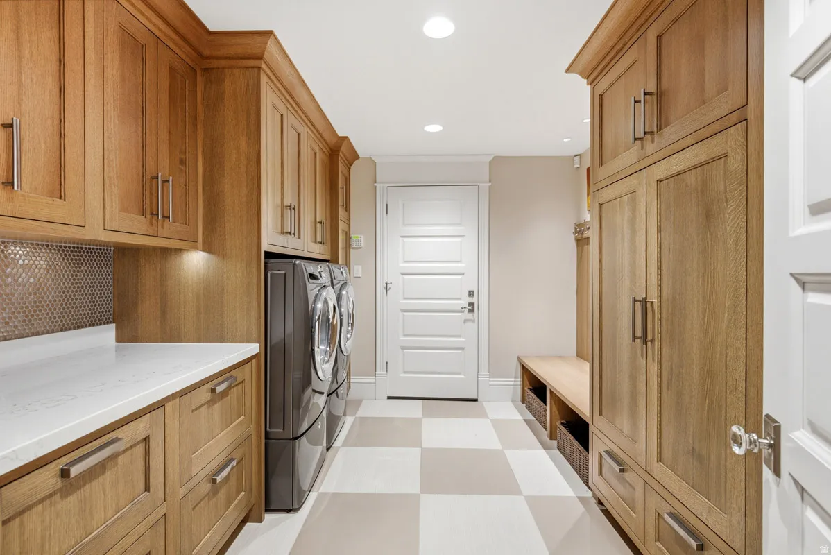 Laundry room featuring extensive wood-finish cabinetry, a white countertop, and a checkerboard floor pattern